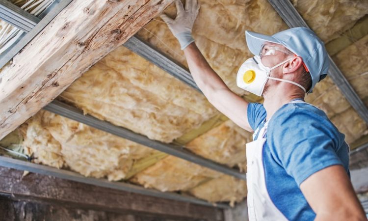 Vakman plaatst minerale wol als dakisolatie aan de binnenkant van een zolderruimte