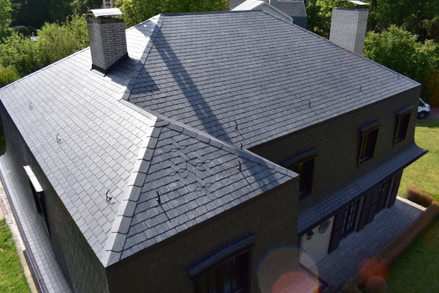 Samengesteld hellend dak met keramische dakpannen en geïntegreerde zonnepanelen bij een gezinswoning