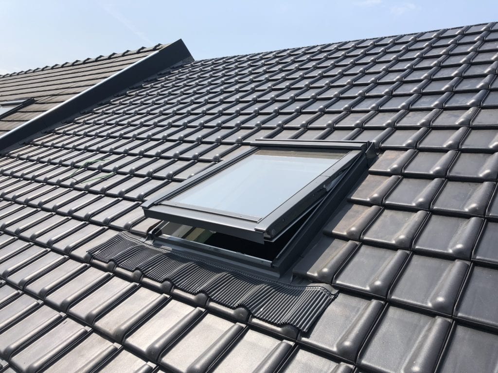 Dakraam laten plaatsen: geopend Velux tuimeldakraam in een zwart pannendak