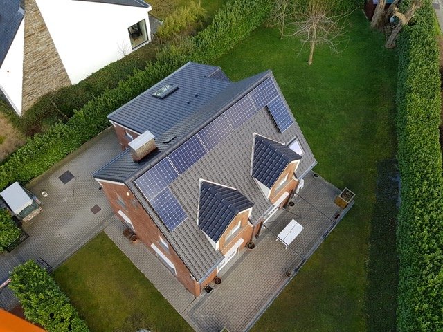 Hellend dak met donkere dakpannen en zonnepanelen op een vrijstaande woning